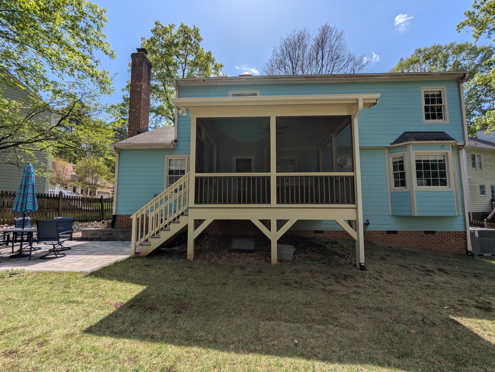 A gabled screened porch added to the back of a light-blue home, built by Metanoia Contracting